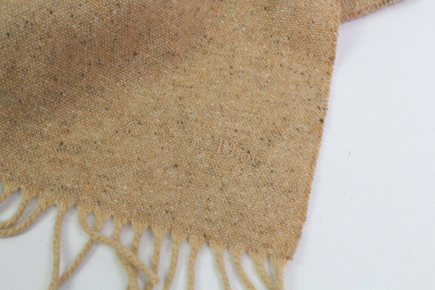 Beige Dior muffler with fringe detailing.