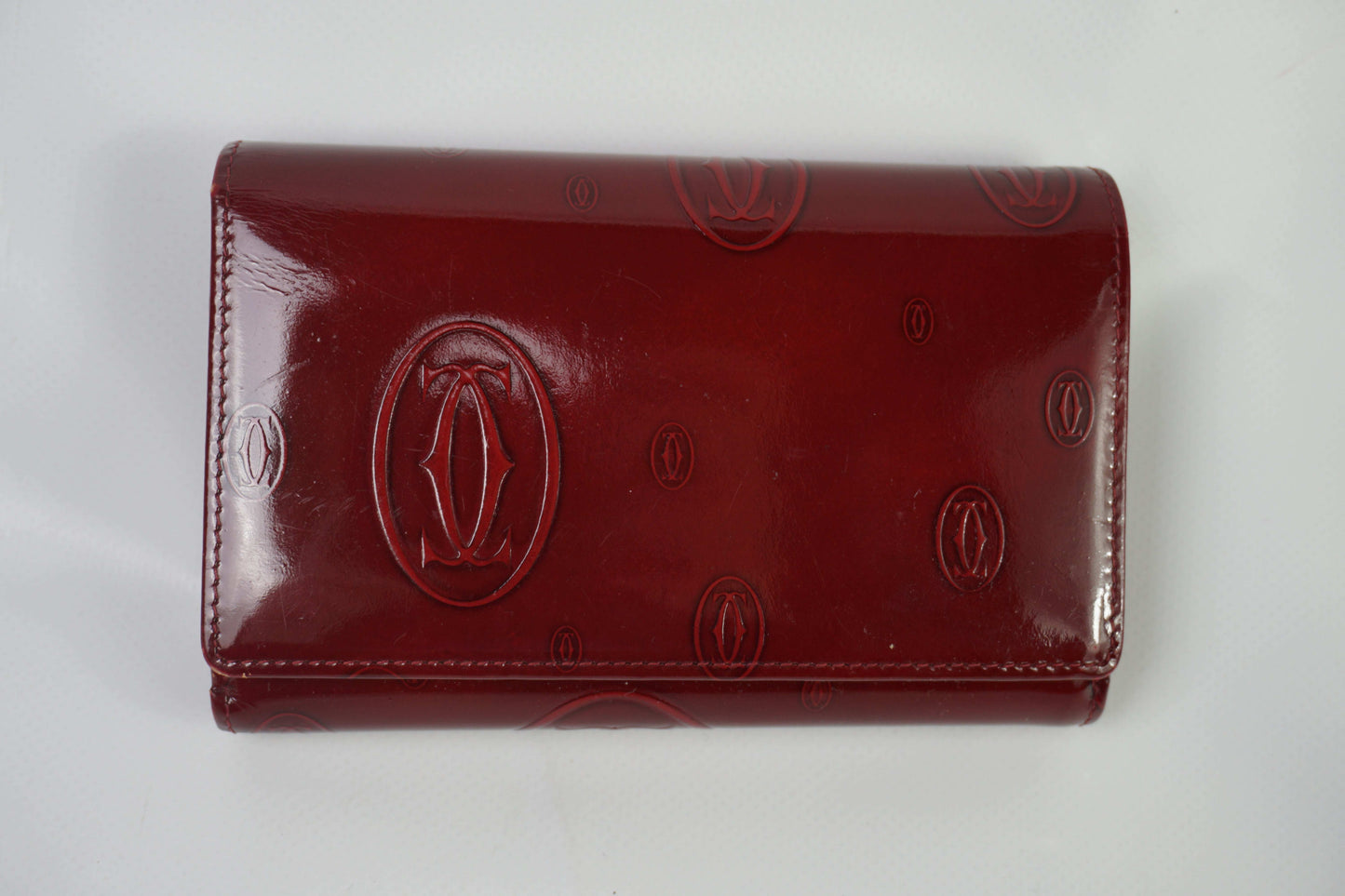 CARTIER leather longwallet in bordeaux red, size 18x13cm, embossed logo design.