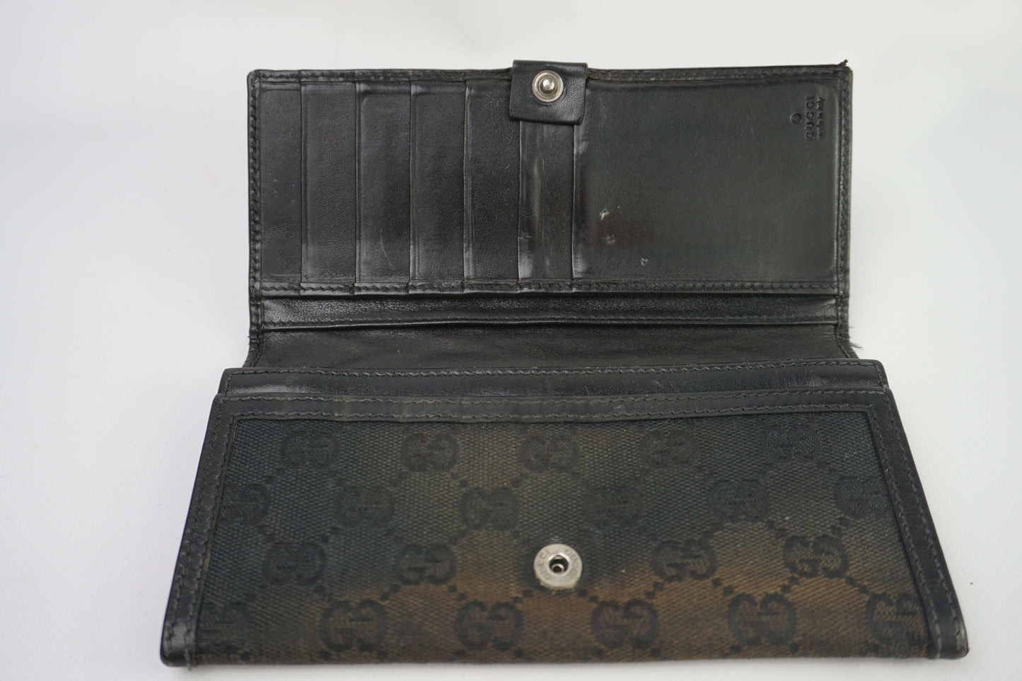GUCCI longwallet black with card slots, features fabric material and subtle wear.