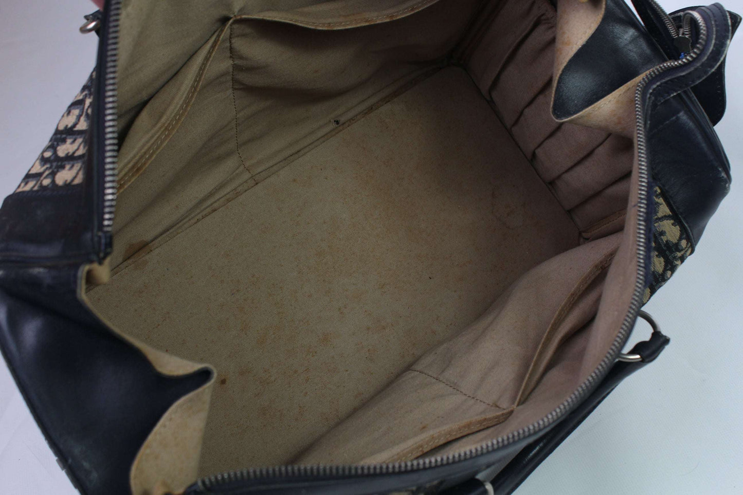 Open interior of a DIOR Keepall Monogram bag, showing canvas and leather with minor flaws.