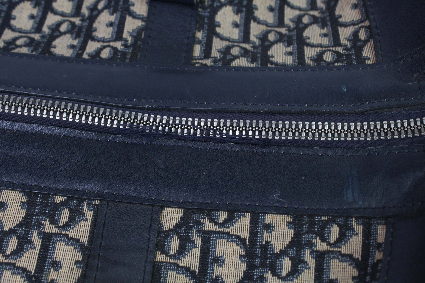 Dior Keepall Monogram in black canvas and leather with monogram pattern and visible zipper flaw.