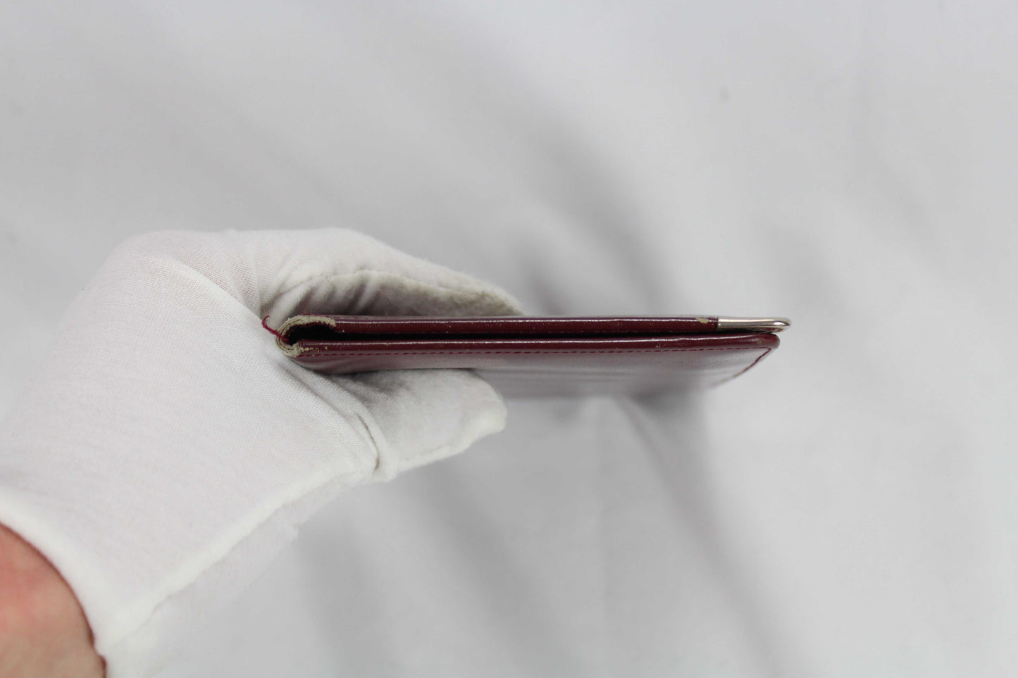 Cartier Wallet in good condition held by a gloved hand.