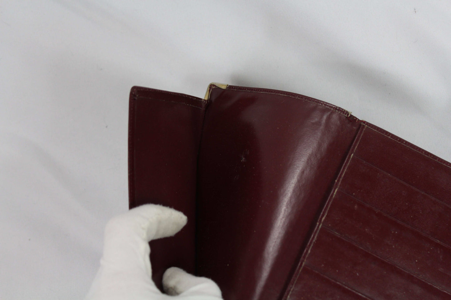 Brown Cartier Wallet in good condition with gloved hand holding it.