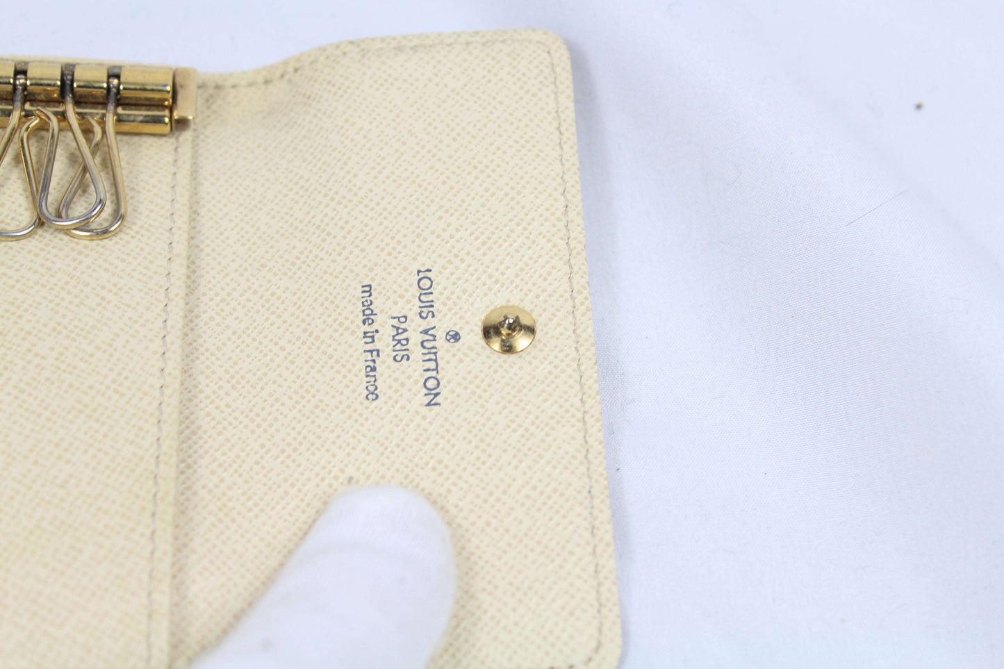 Louis Vuitton Damier Keyholder in brown canvas, condition 7/10, with visible flaws, showcasing interior hooks and brand stamp.