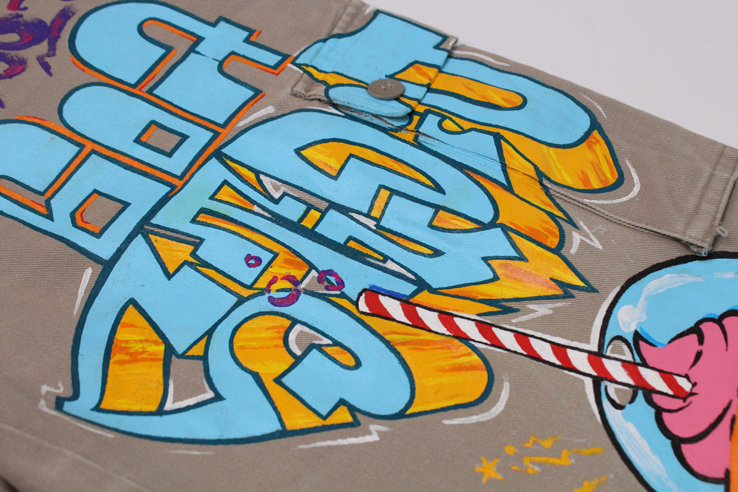 Custom painted jeans with graffiti design in colors of beige, orange, and blue.