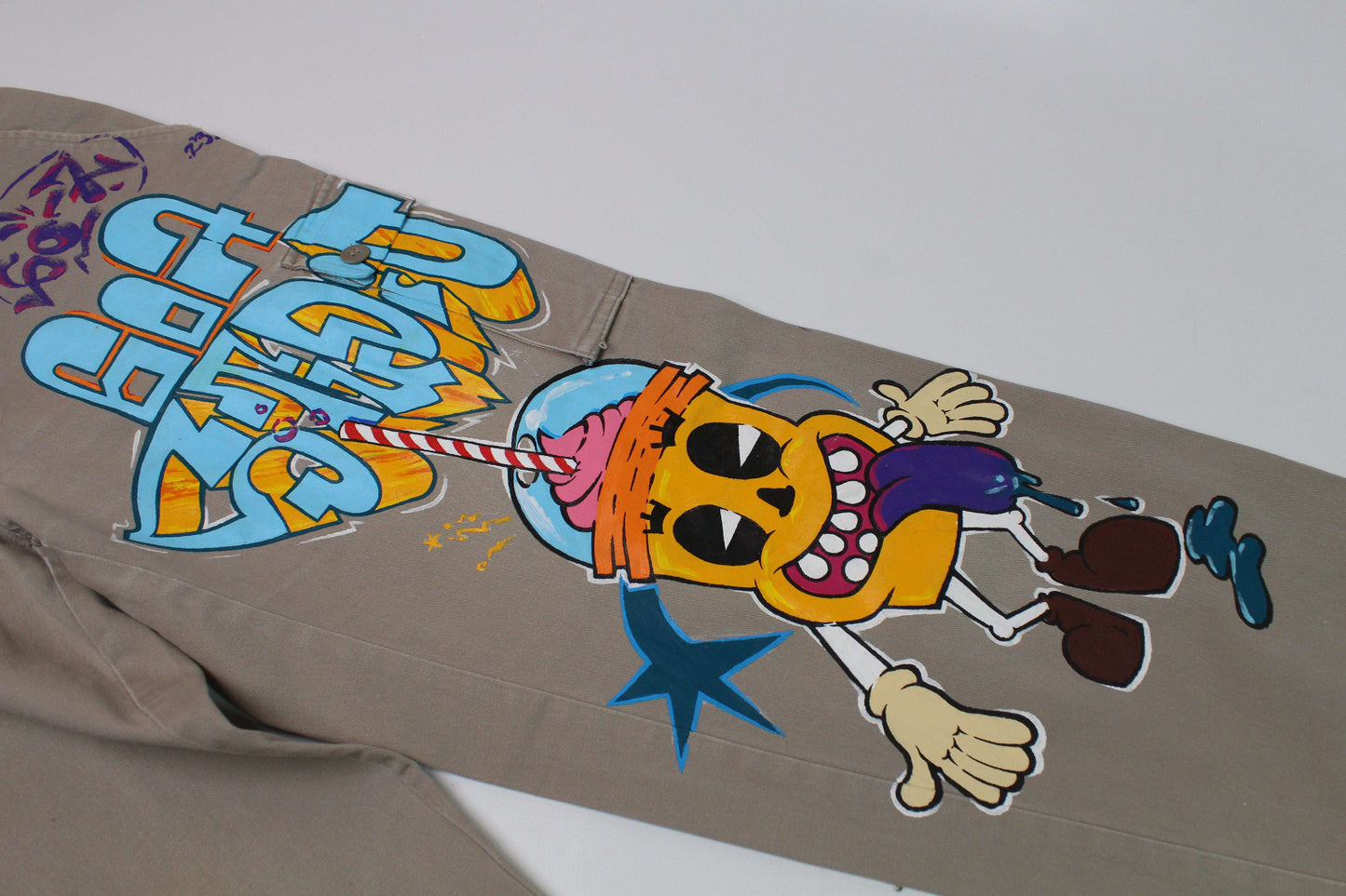 Custom painted jeans with colorful cartoon design, straight fit, small size, beige and orange/blue colors.