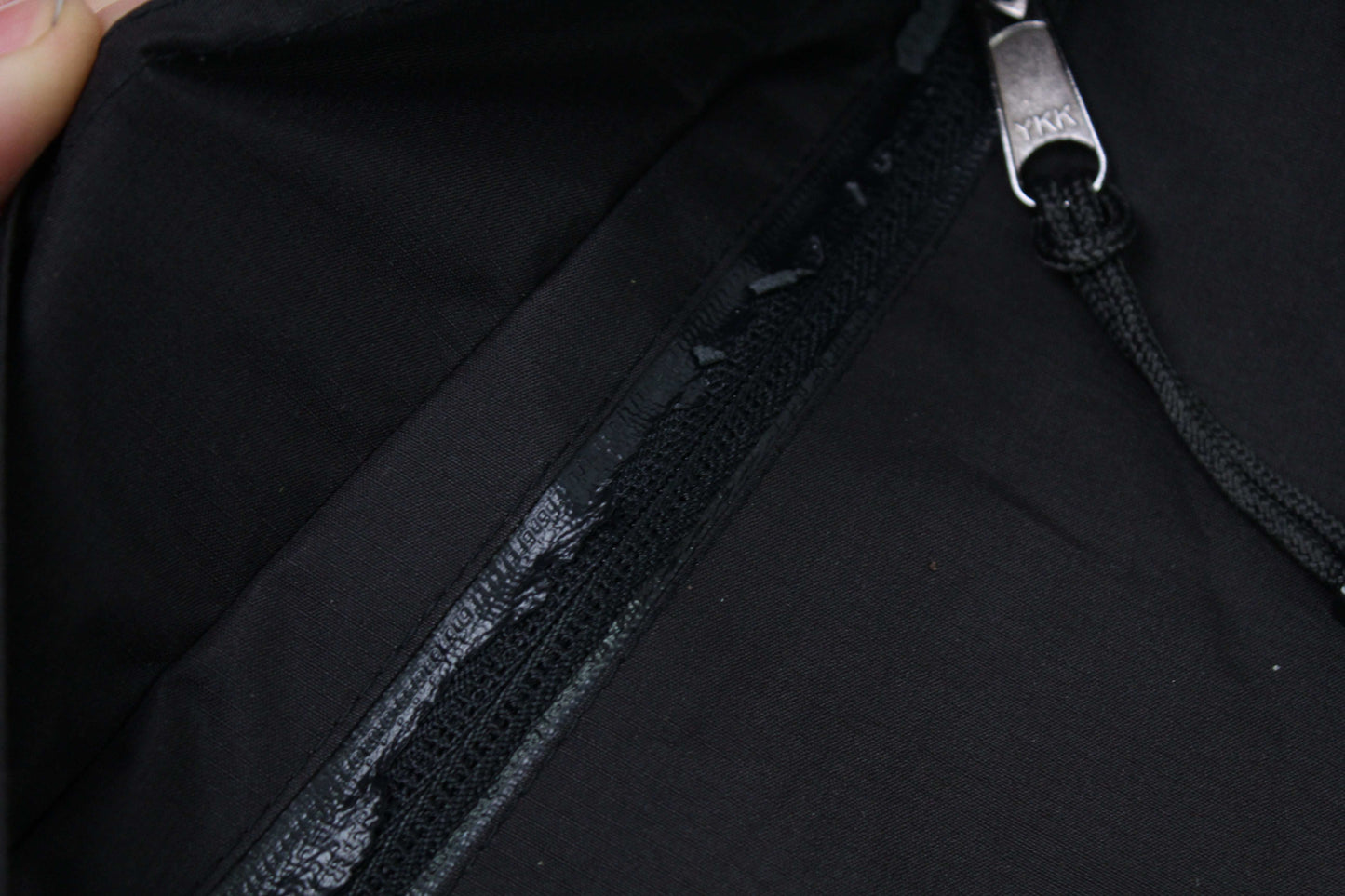 Close-up of a black THE NORTH FACE Gore Tex Jacket with visible zipper wear.