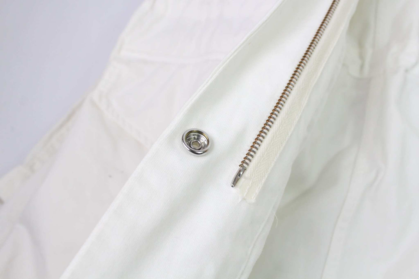 Close-up of white MAISON MARGIELA jacket with zipper detail.