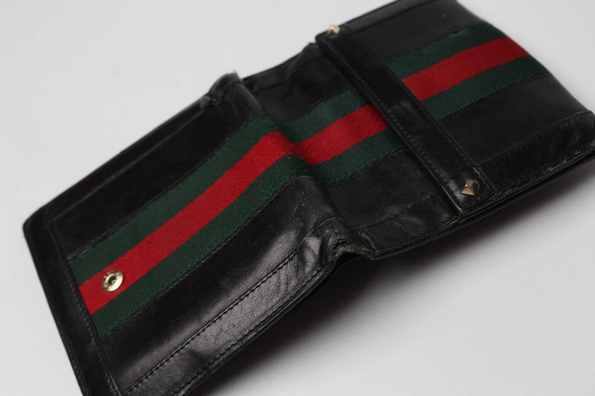 Black GUCCI wallet with red and green stripe, made from leather and fabric.