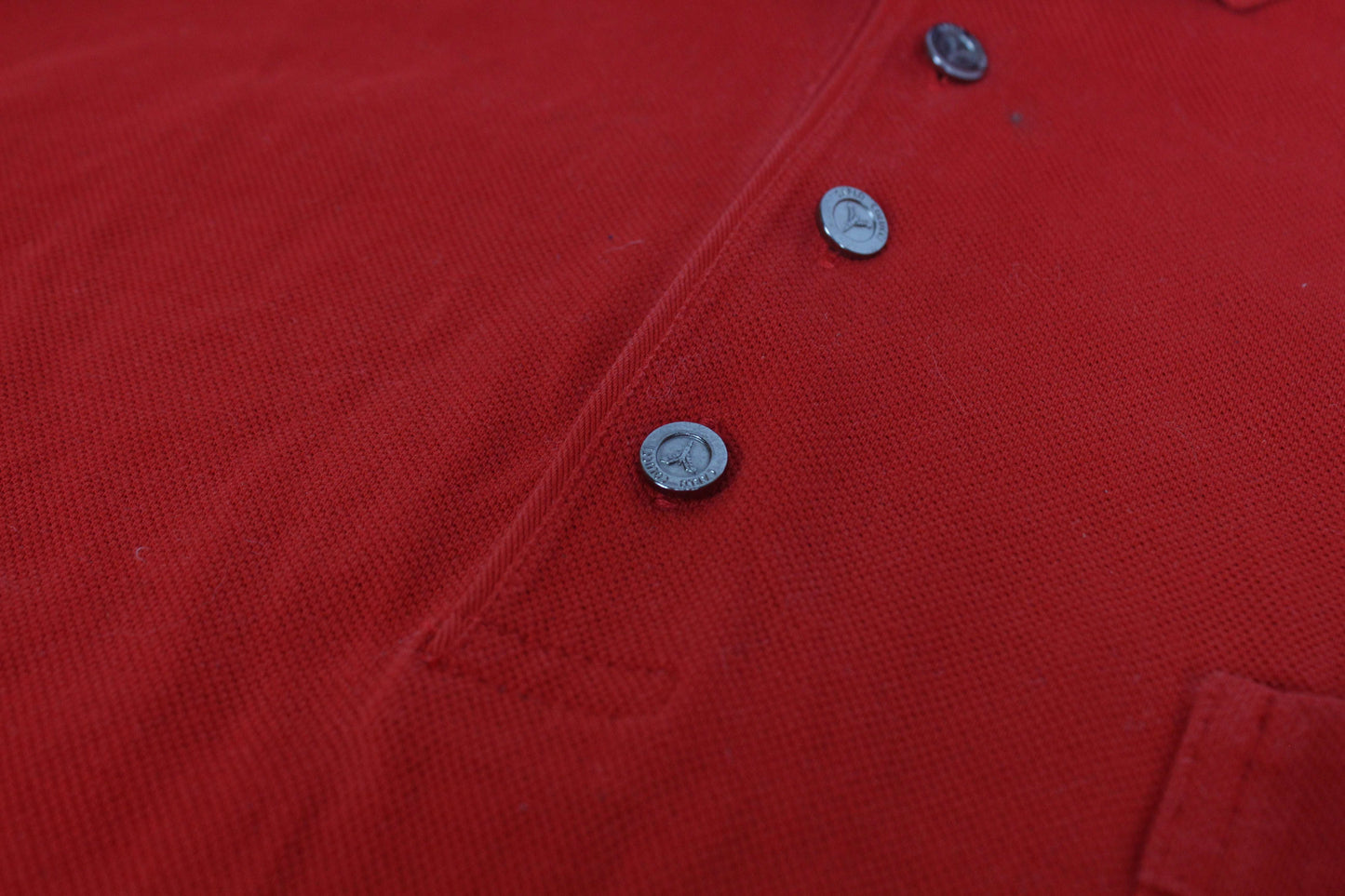 Carlo Colucci red shirt with black buttons, close-up.