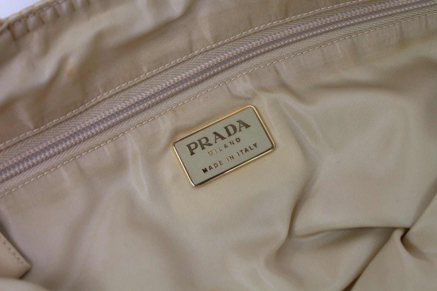 Prada Shopper Gold bag interior label showing "Made in Italy" with beige fabric background.