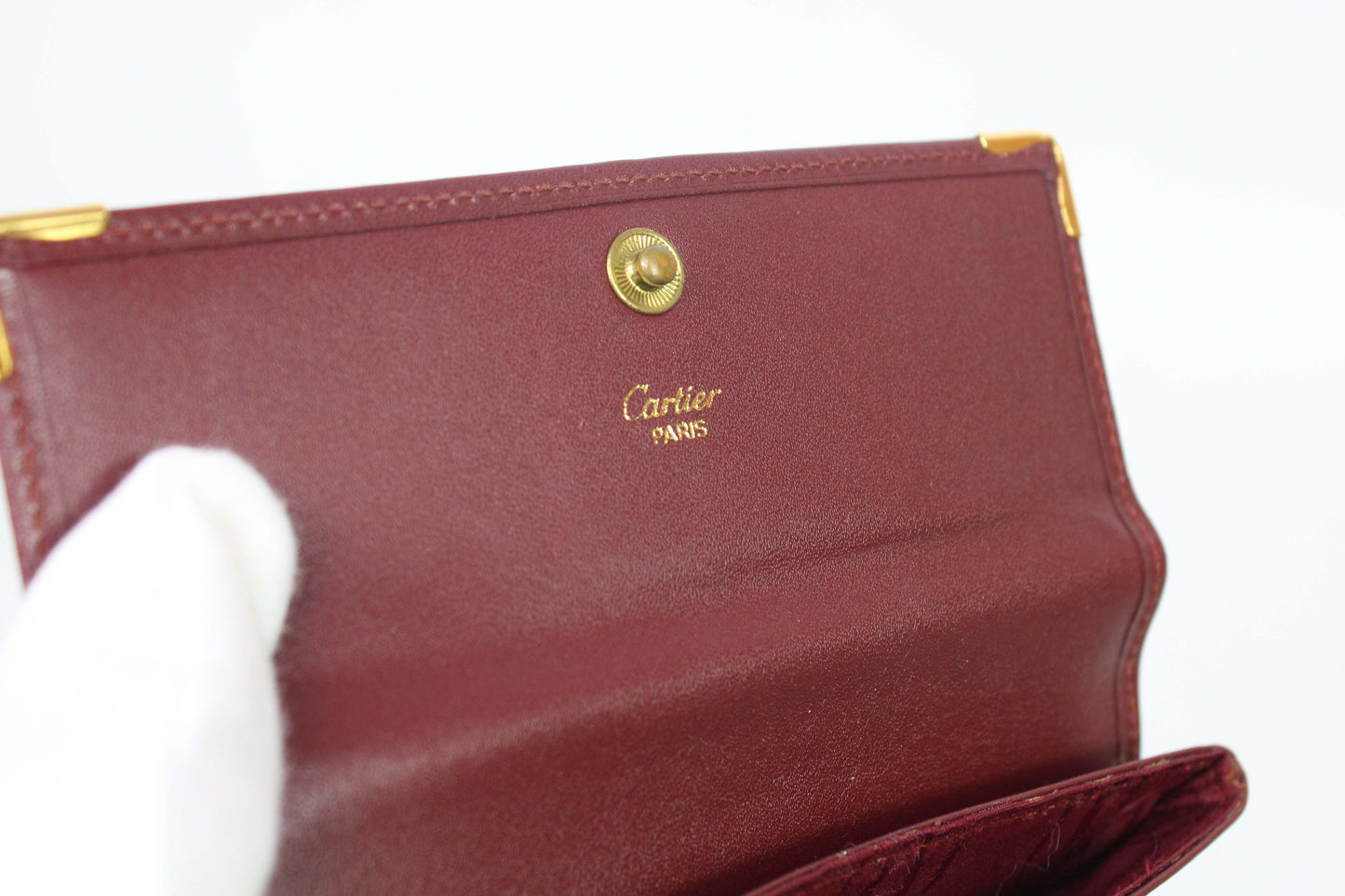 Bordeaux red Cartier Portmonee in leather, size 16x10cm, showing interior with logo and snap closure.