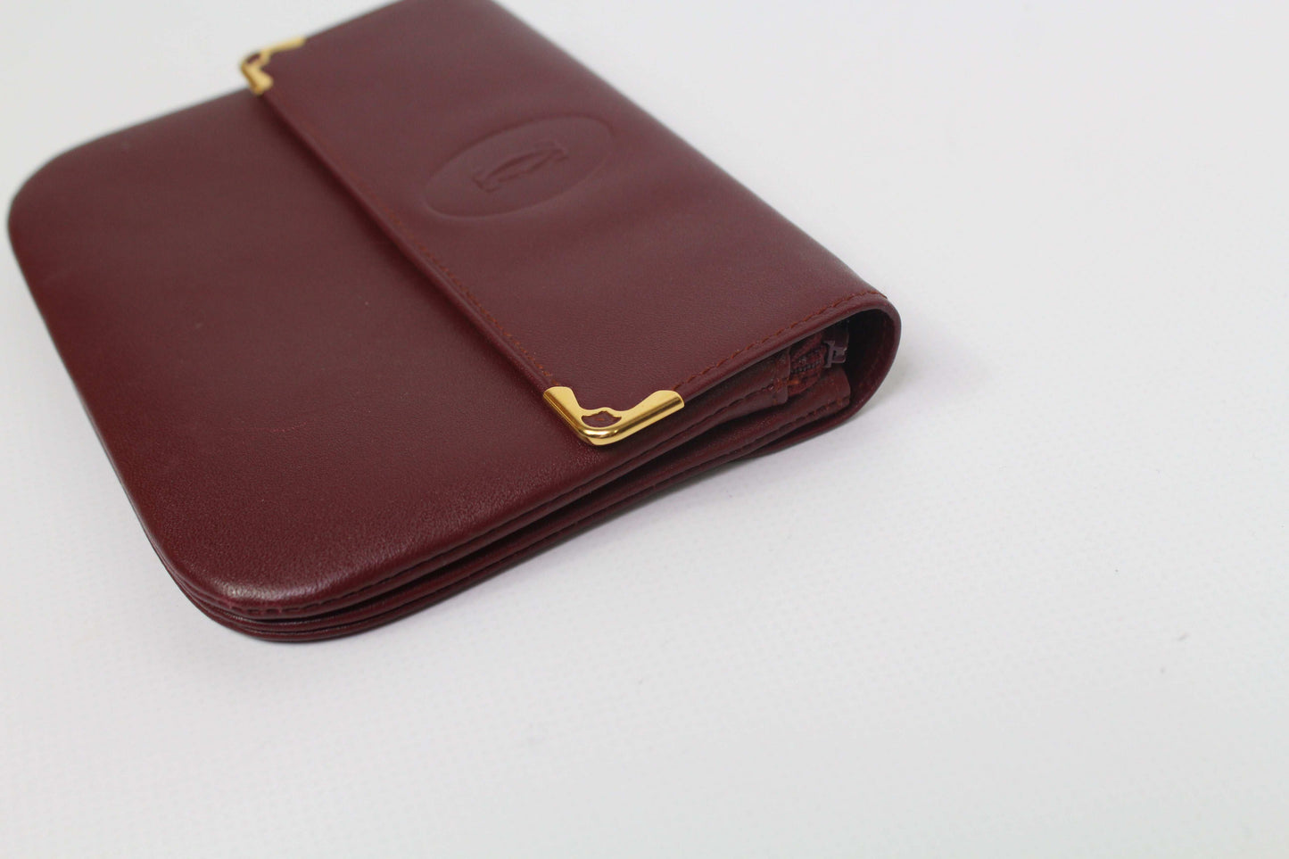 Bordeaux red leather Cartier Portmonee wallet with gold accents, size 16x10cm.